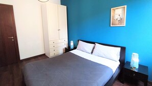 Un dormitorio con cama, armario, mesita de noche y un cuadro en la pared.