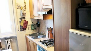 Una cocina con armarios de madera, un refrigerador de acero inoxidable, una estufa y un microondas.