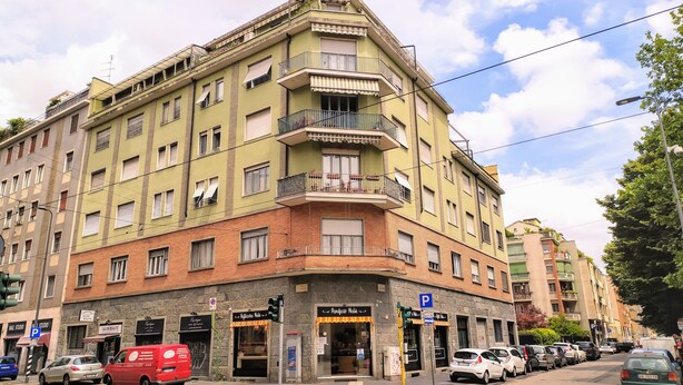 Un edificio de varios pisos con entrada en esquina, que cuenta con una tienda en la planta baja con un letrero que dice "Salon Beaute".