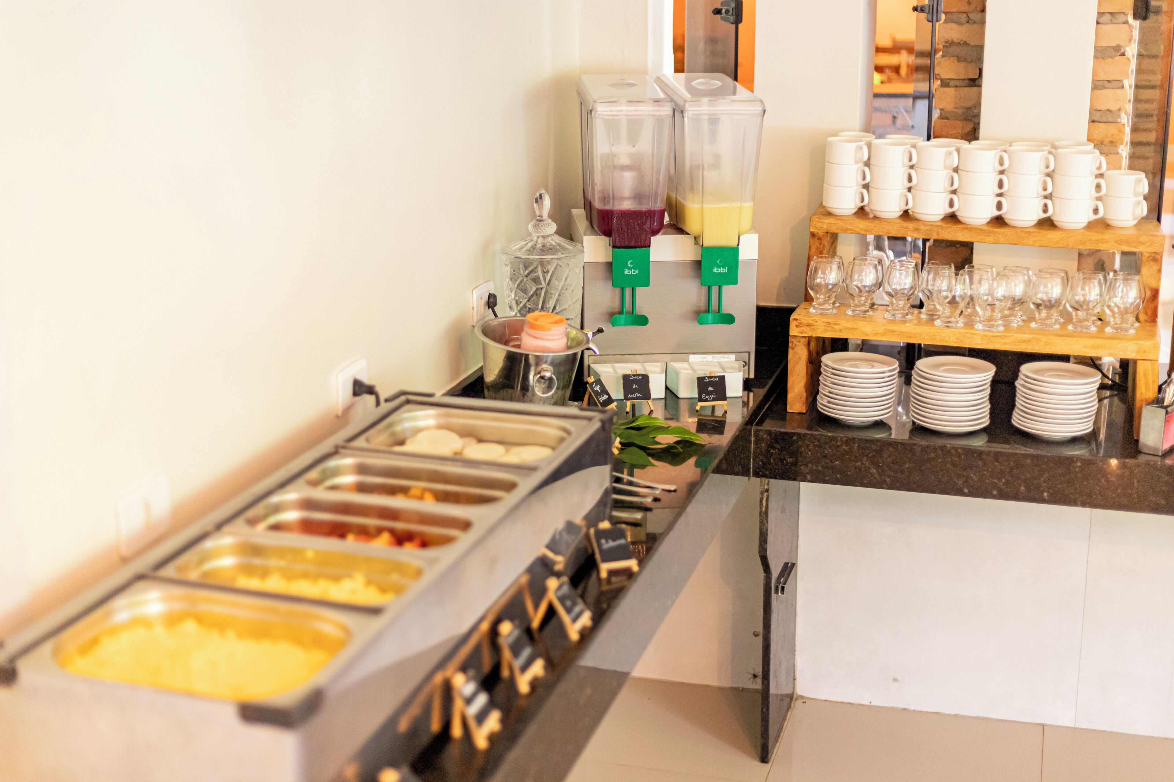 A buffet area with multiple food dispensers, a coffee station, and a glassware display.