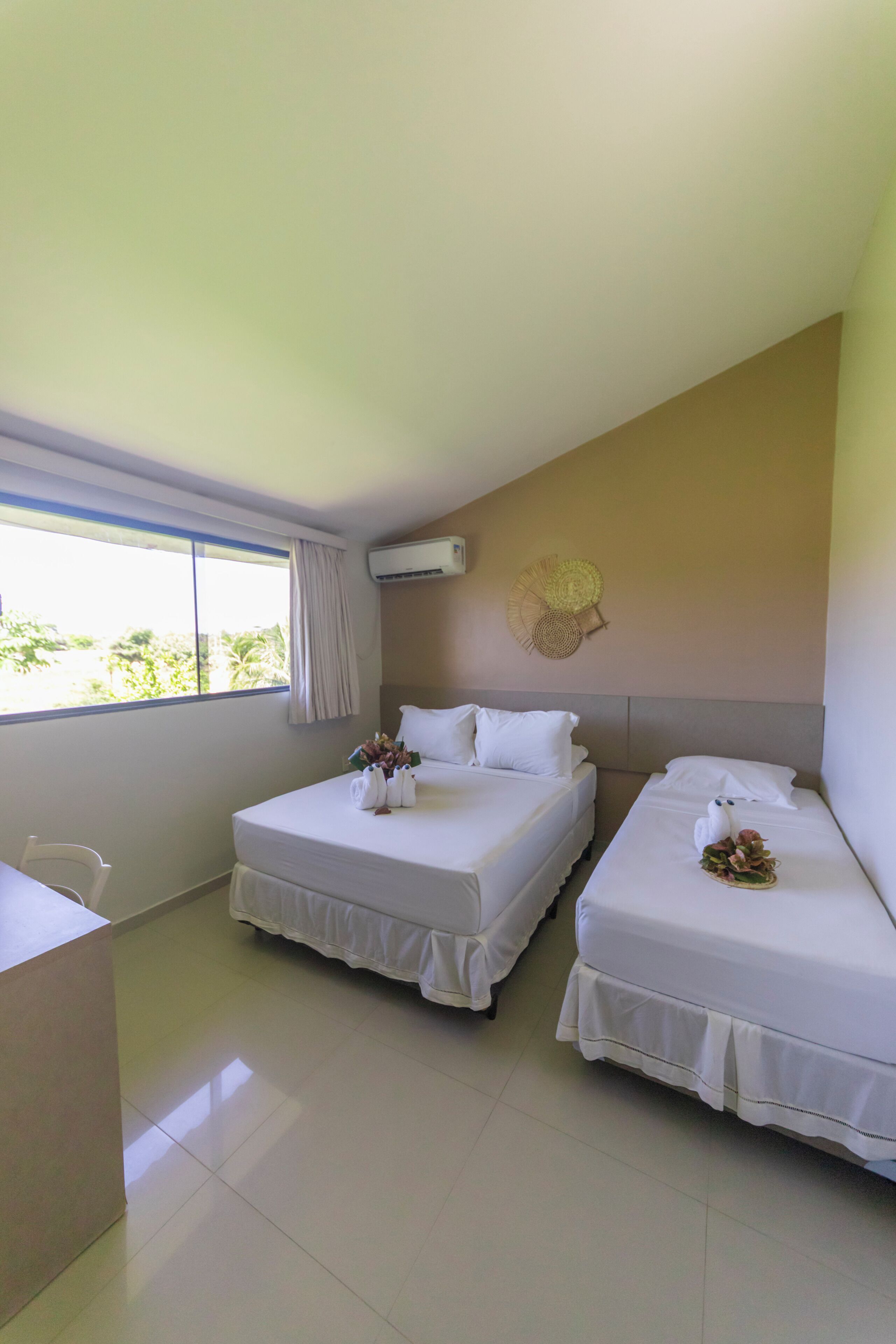 A hotel room with two beds, a desk, and a window with curtains.