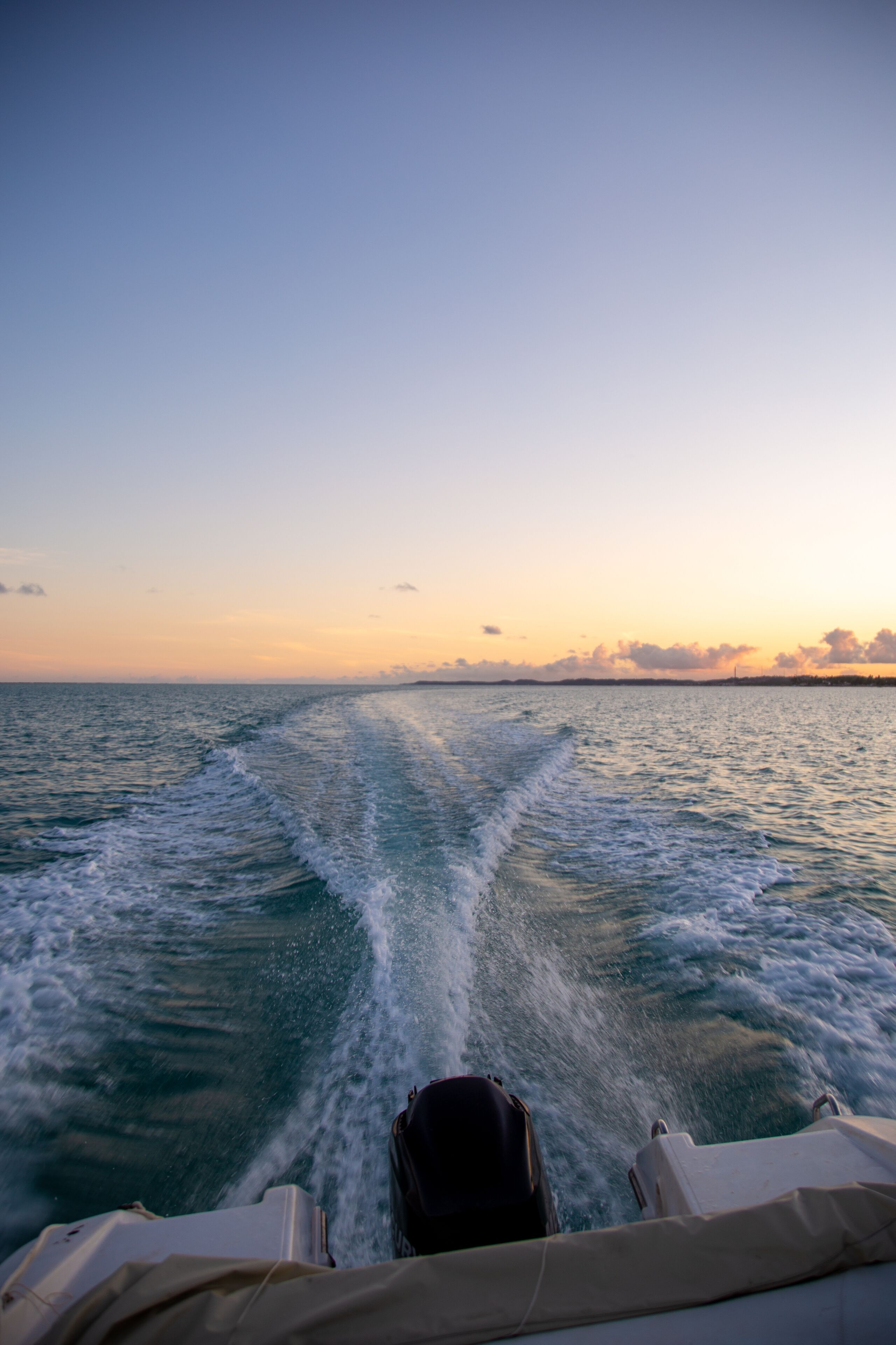 A boat's wake in the ocean with a clear sky.