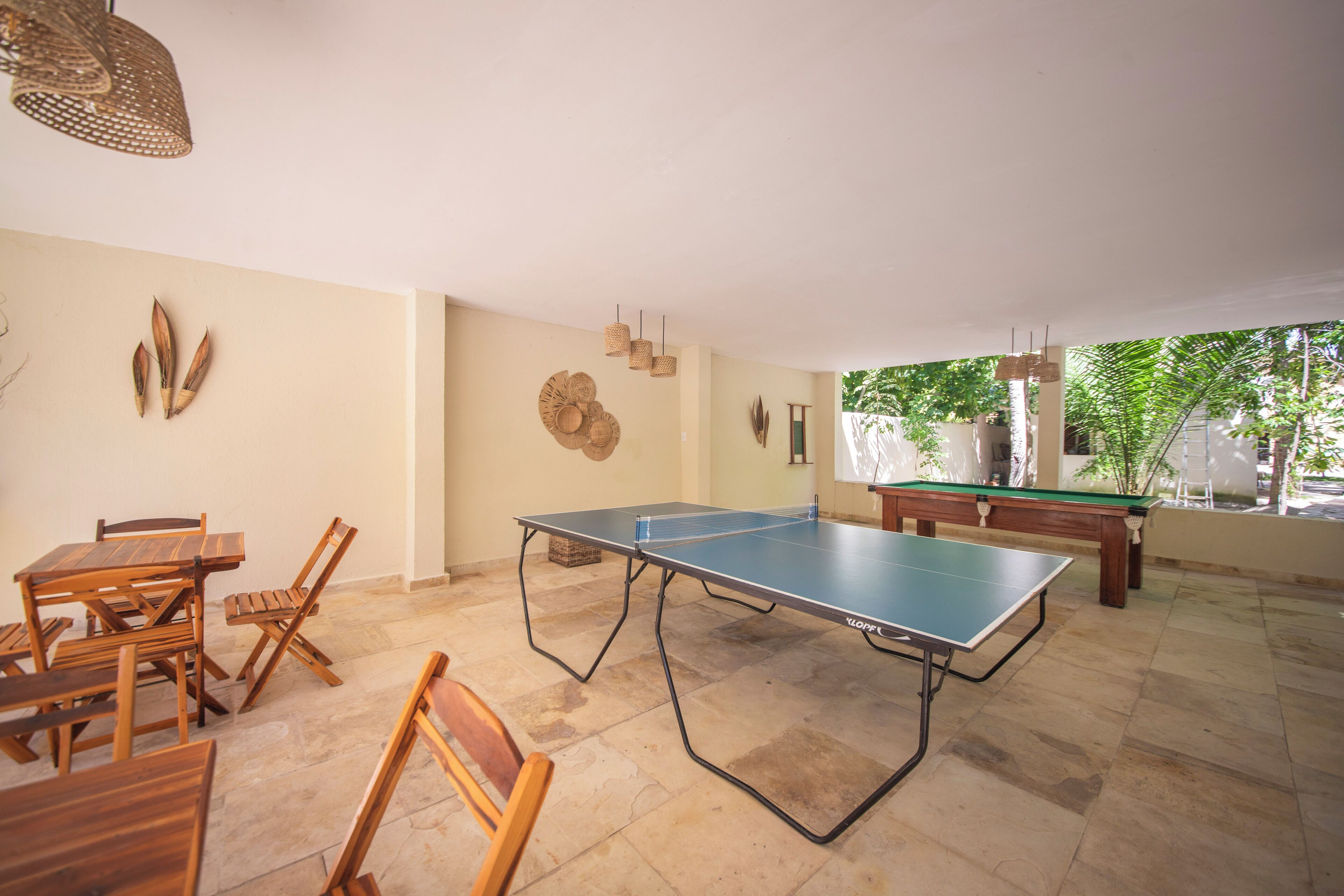 A spacious indoor area with a ping pong table, wooden chairs, and a pool table.