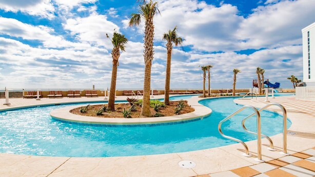 A pool area with palm trees, lounge chairs, and a water slide. - Beachfront,POB II #601 Parking Level,4 Bedroom, Immaculate, Great Views
 (Orange Beach)