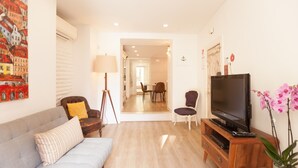 A living room with a sofa, chairs, a TV, and a wooden cabinet.