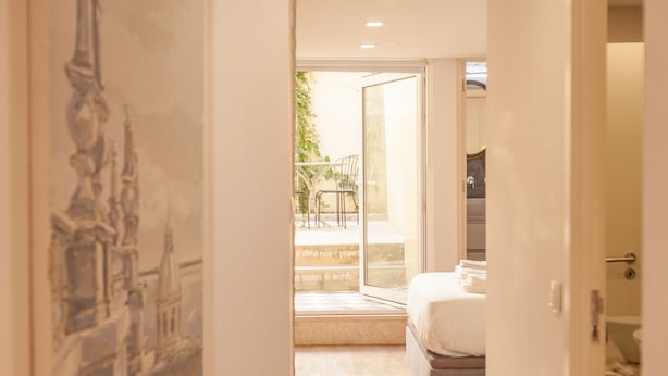 A bedroom with a bed, a window, and a door leading to a balcony.