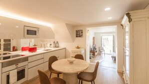 A modern kitchen with white cabinetry, a round dining table, and brown chairs.