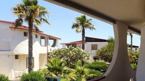 Vista di un edificio con facciata bianca, palme e un'area giardino.