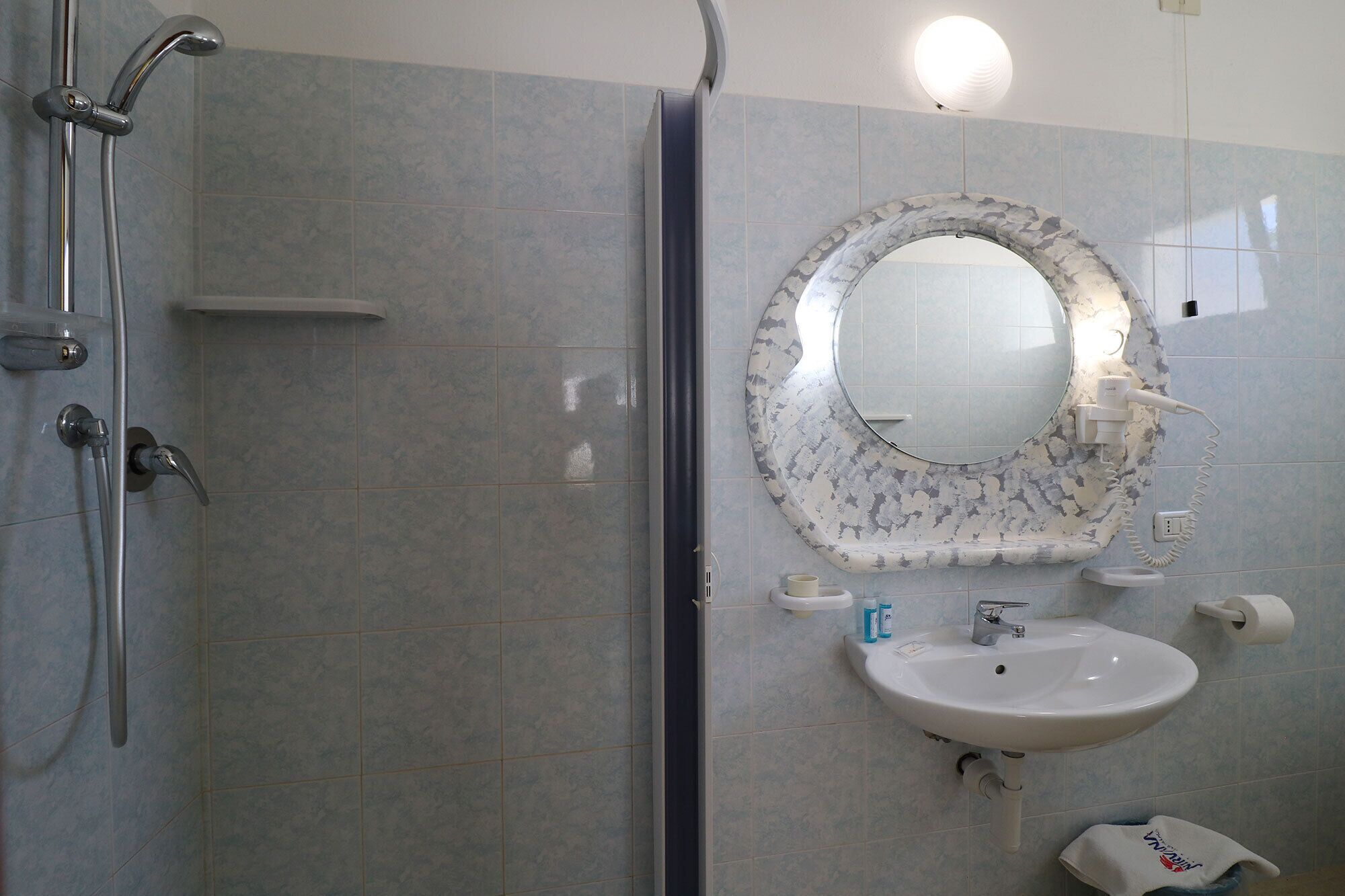 A bathroom with a shower, sink, and mirror.