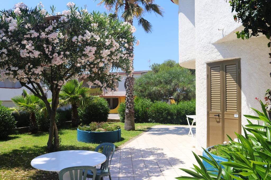 Un patio con una mesa y sillas, un árbol en flor y un edificio con una puerta.