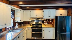A kitchen with white cabinets, stainless steel appliances, and a black refrigerator. - Perfect Lake or Mountain Getaway Less Than 5 Minutes Away (Sunapee)
