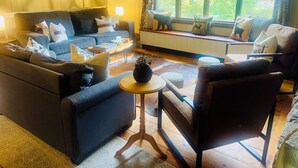 A cozy living room with a blue sofa, a wooden coffee table, and a window with a view of greenery. - Perfect Lake or Mountain Getaway Less Than 5 Minutes Away (Sunapee)
