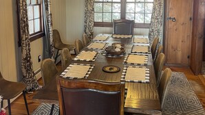 A dining room with a long wooden table, patterned tablecloths, and a chandelier. - Perfect Lake or Mountain Getaway Less Than 5 Minutes Away (Sunapee)