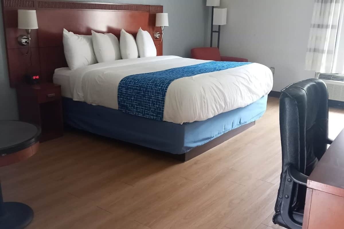 Une chambre d’hôtel avec un grand lit, un bureau et une chaise.