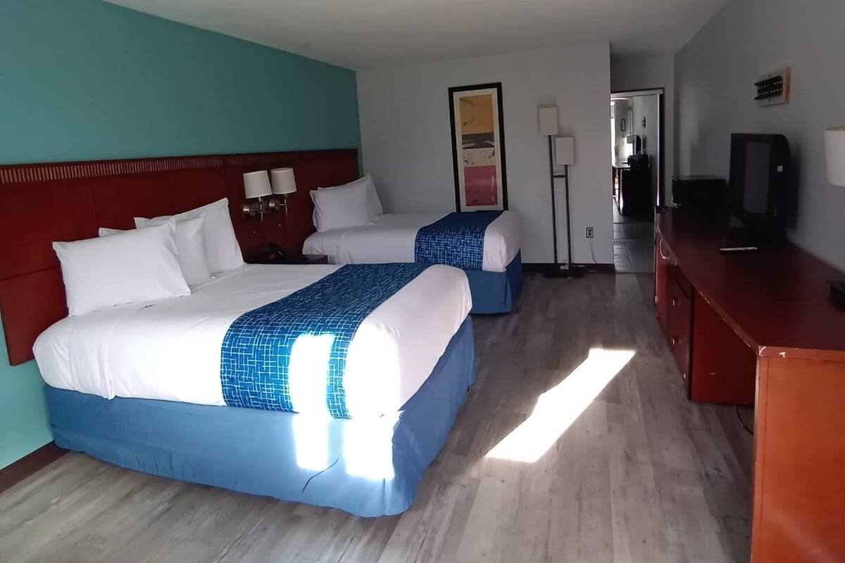 Une chambre d’hôtel avec deux lits, un bureau et une télévision.