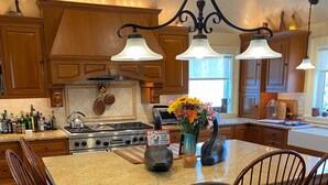 A kitchen with wooden cabinets, a granite countertop, a gas stove, and a chandelier. - Spacious Kennebunkport River property, family/pet friendly, 2 miles to beaches (Kennebunk)