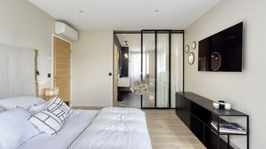 Ein modernes Schlafzimmer mit einem großen Bett, einem Kleiderschrank, einem Schminktisch und einem an der Wand befestigten Fernseher.