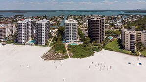 A coastal resort area with high-rise buildings, a sandy beach, and a marina. - Gullwing 505 3BR Oasis: Beachfront & Lanai (Fort Myers Beach)