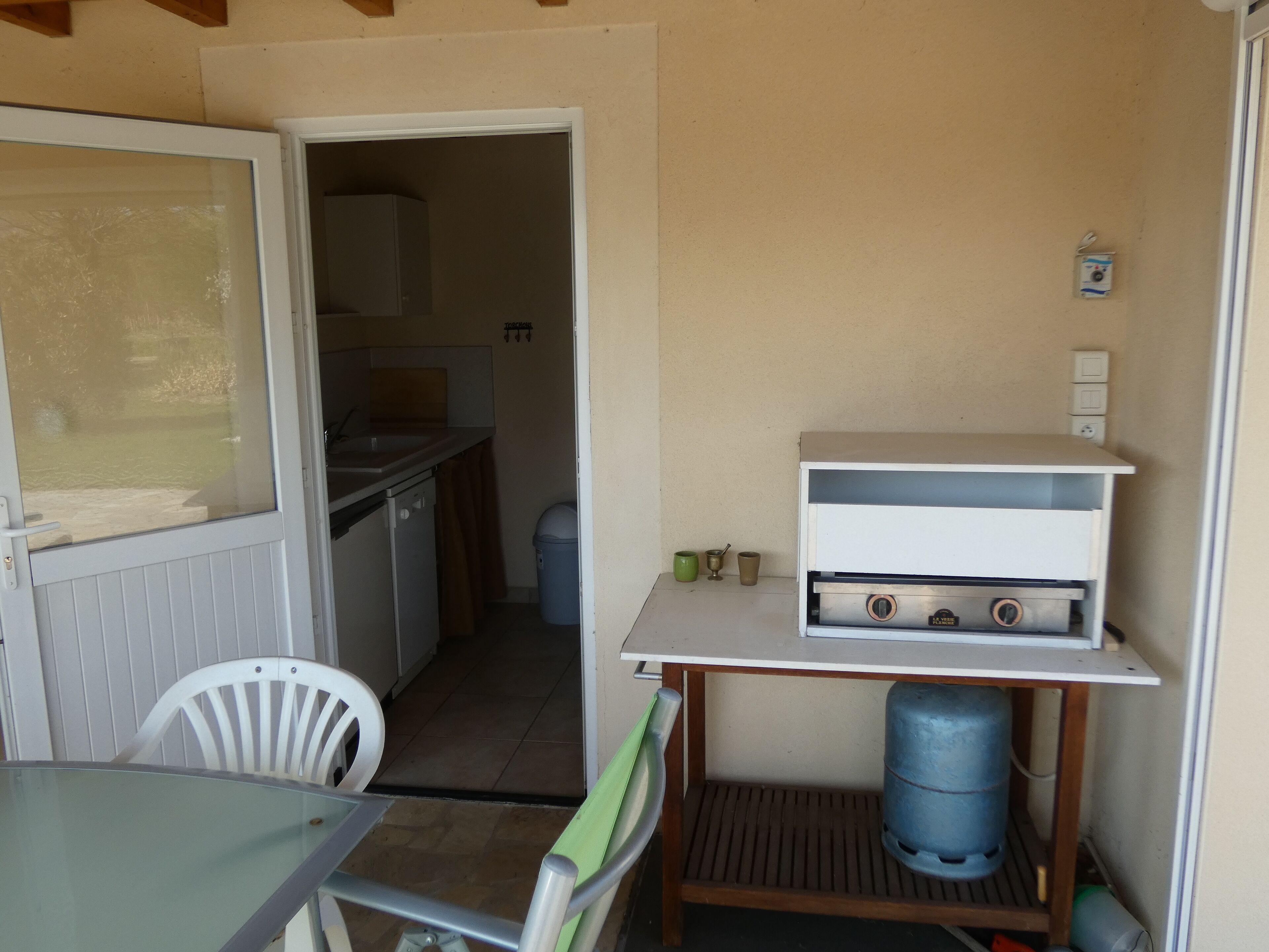 Uma cozinha compacta com forno embutido, uma mesa pequena e uma cadeira.