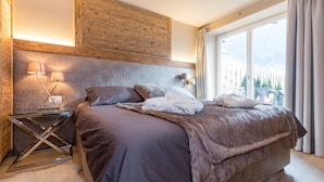 Un dormitorio moderno con una cama grande, una mesita de vidrio y un cabecero de madera.