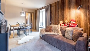 Una sala de estar moderna con una pared de acento de madera, un sofá con cojines mullidos y una zona de comedor con mesa y sillas.