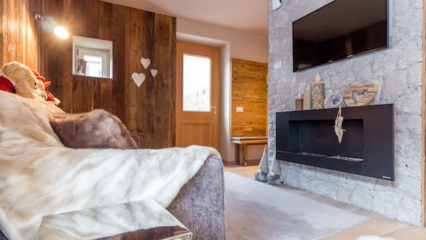 Una sala de estar acogedora con chimenea, paredes de madera y un sofá mullido.