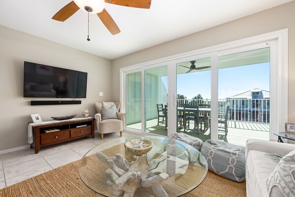 A spacious living room with a large flat-screen TV, a glass coffee table, and a comfortable seating area. - Hidden Gem, South of 30A w/ Private Beach Access (Panama City Beach)