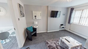 Relax in a comfortable seating area with a sofa, flat-screen TV, and coffee table.