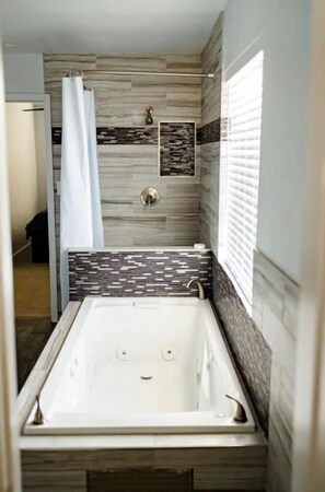 Une petite salle de bain avec une baignoire, un rideau de douche et une fenêtre.