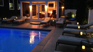 Ein Poolbereich mit Liegestühlen und einer überdachten Sitzgruppe mit Kamin.