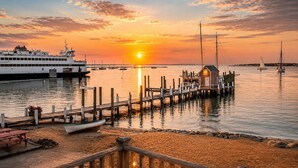 Una vista al atardecer con un muelle, un edificio pequeño y un barco.