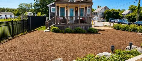 A two-story house with a front porch, a fenced yard, and a driveway.