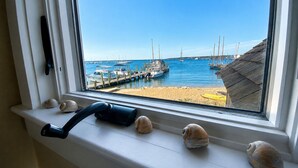 Una ventana con vista a un puerto deportivo, barcos y una playa de arena.