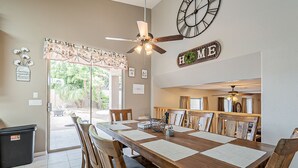 A dining area with a wooden table, chairs, and a ceiling fan. There is a 'HOME' sign on the wall and a trash bin near the door. - Very Large 5br, Arrowhead Ranch, Games, Quiet, Relaxing (Glendale)