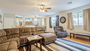 A living room with a sectional sofa, a recliner, a coffee table, a ceiling fan, and a view of the backyard through large windows. - Very Large 5br, Arrowhead Ranch, Games, Quiet, Relaxing (Glendale)
