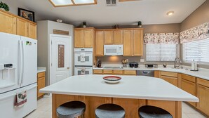 A modern kitchen with wooden cabinets, a central island, and a white countertop. - Very Large 5br, Arrowhead Ranch, Games, Quiet, Relaxing (Glendale)