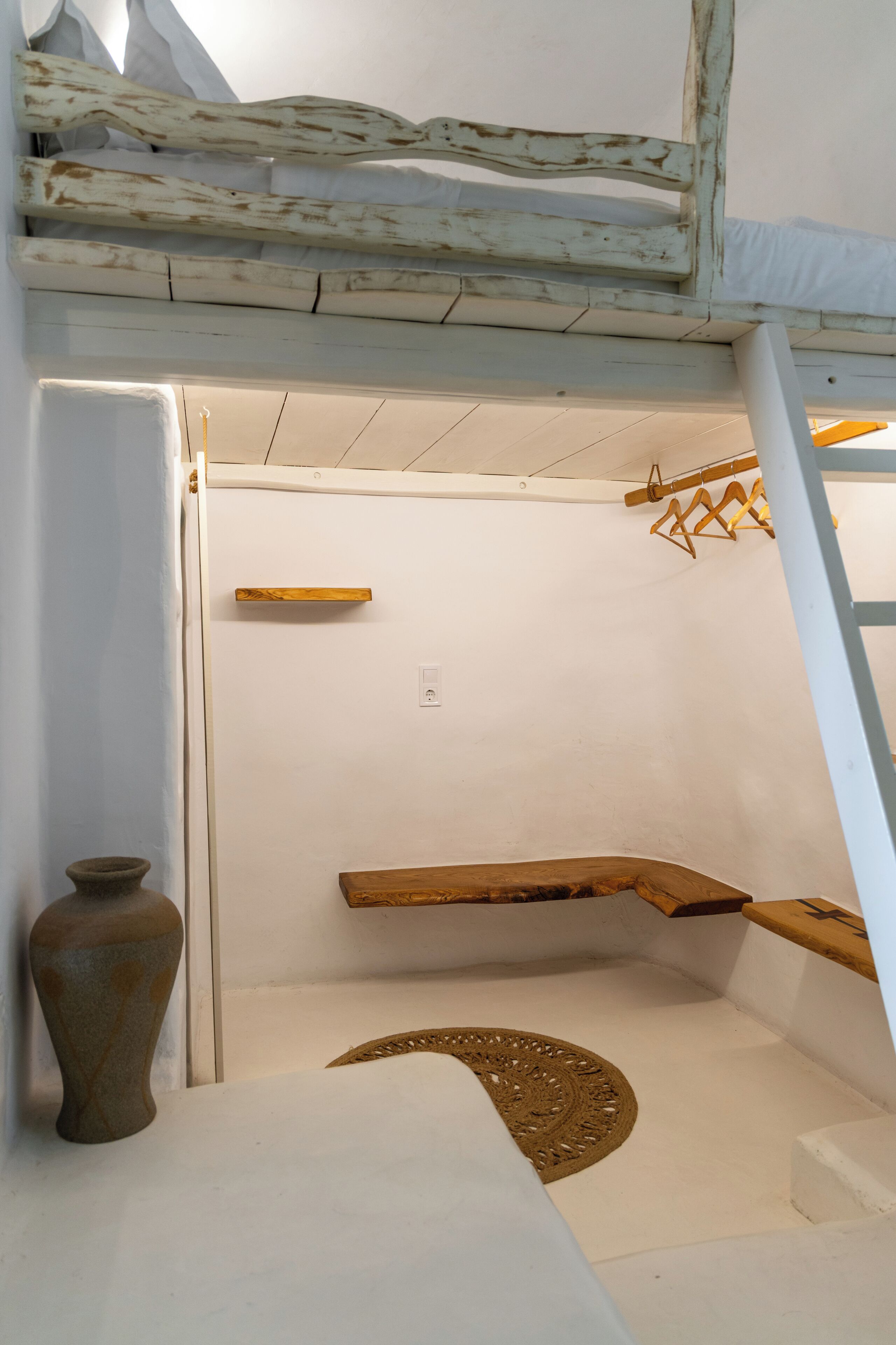 A room with a bunk bed, a small shelf, a decorative rug, and a vase.