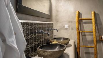 Une salle de bain dotée d’un grand miroir, de deux vasques en pierre, d’une échelle en bois et de carreaux de sol à motifs.