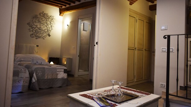 Un dormitori amb dos llits, una tauleta de nit amb una làmpada, una obra d'art a la paret i una porta que dona a una altra habitació.