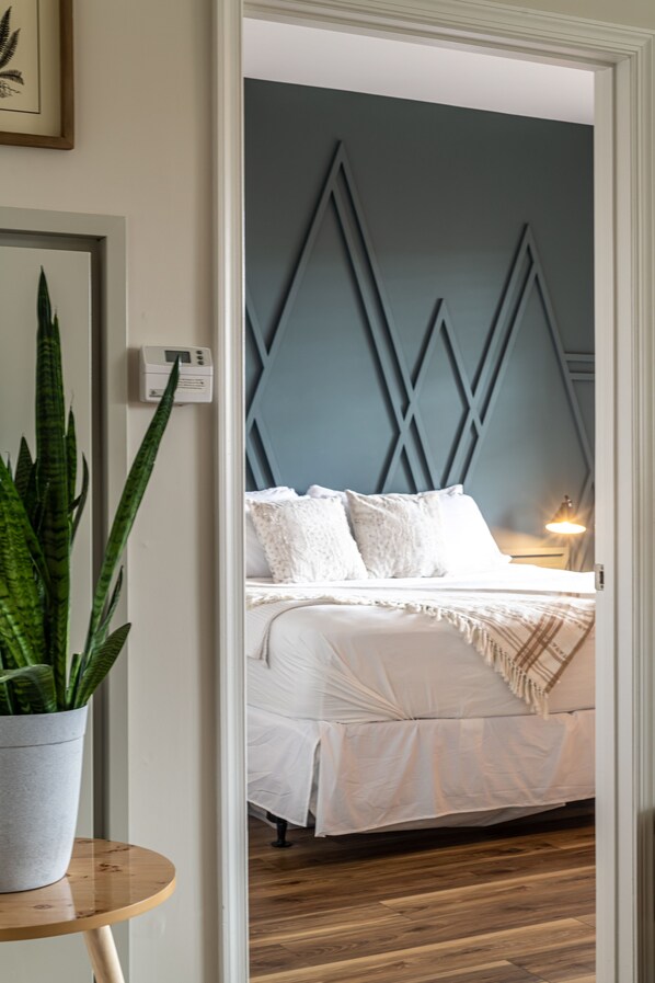 Une chambre à coucher avec un lit, une plante en pot et un thermostat fixé au mur.