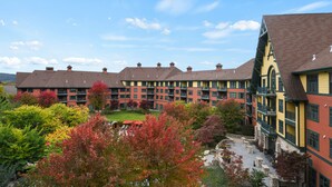 A multi-story hotel with a courtyard, featuring a mix of brick and wood exteriors, and surrounded by trees with autumn foliage.