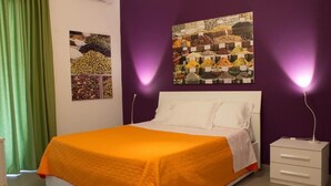 A bedroom with a bed, a nightstand, and two wall-mounted lamps.