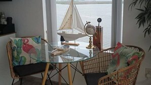 Spisestue med et glasbord og fletstole, en model af en sejlbåd og en globe på bordet.