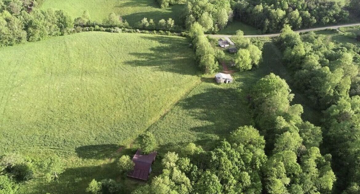 Luchtbeeld van een landelijk gebied met velden, bomen en enkele gebouwen.