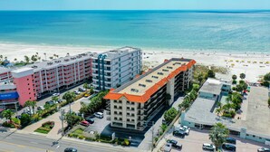 A hotel with multiple floors, a parking lot, and a beach view.