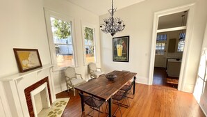 Une salle à manger avec une table en bois, des chaises et un lustre. On y trouve également une cheminée et une carte accrochée au mur.