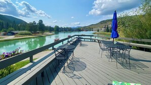 A wooden deck with outdoor seating overlooking a river, surrounded by greenery and buildings. - Montezuma 1770 (Keystone)