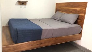 Un letto singolo con struttura in legno, testiera, materasso grigio e coperta blu.