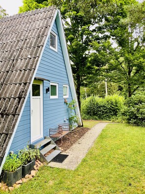 A blue house with a sloped roof, a front door, and a small porch with steps leading up to it.