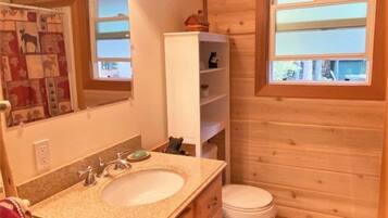 A wooden cabin bathroom with a sink, toilet, and shelves.